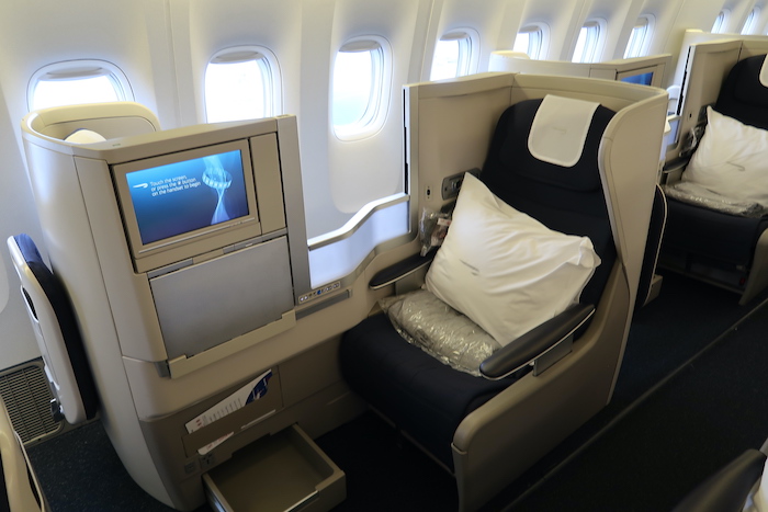 a seat with a pillow and a monitor on the side of the plane