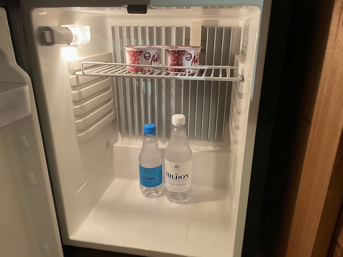 a small refrigerator with two bottles of yogurt and yogurt