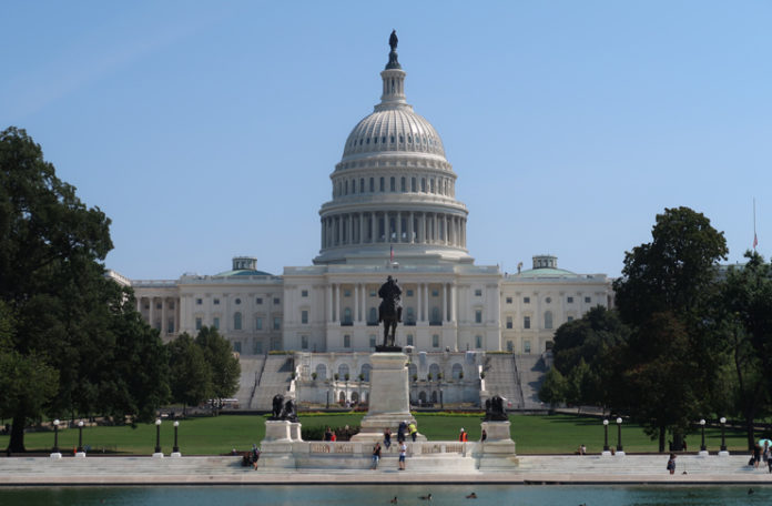 a statue of a man on a statue in front of a white building with United States Capitol in the background