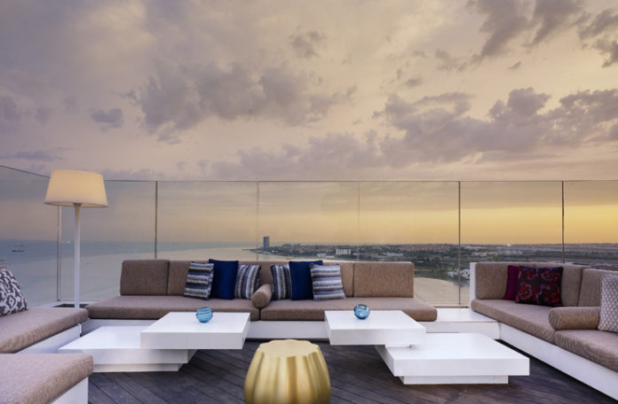 a couches and tables on a deck overlooking a city