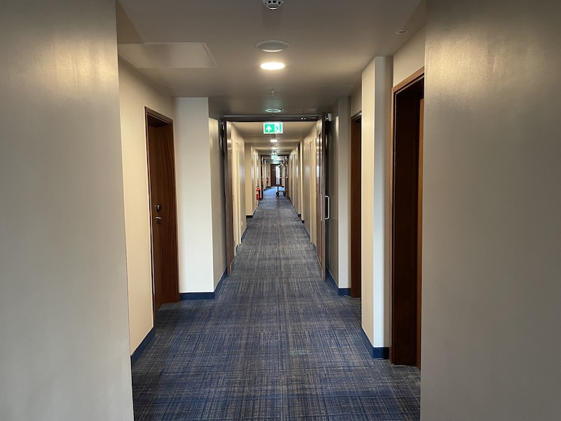 a hallway with doors and a green sign