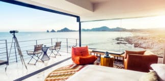 a room with a bed and chairs overlooking the ocean