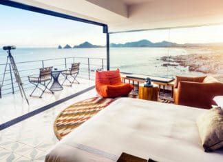 a room with a bed and chairs overlooking the ocean