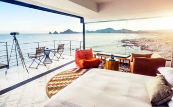 a room with a bed and chairs overlooking the ocean