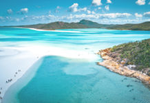 a beach with blue water and hills with Whitehaven Beach in the background