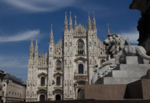 a stone lion statue in front of Milan Cathedral