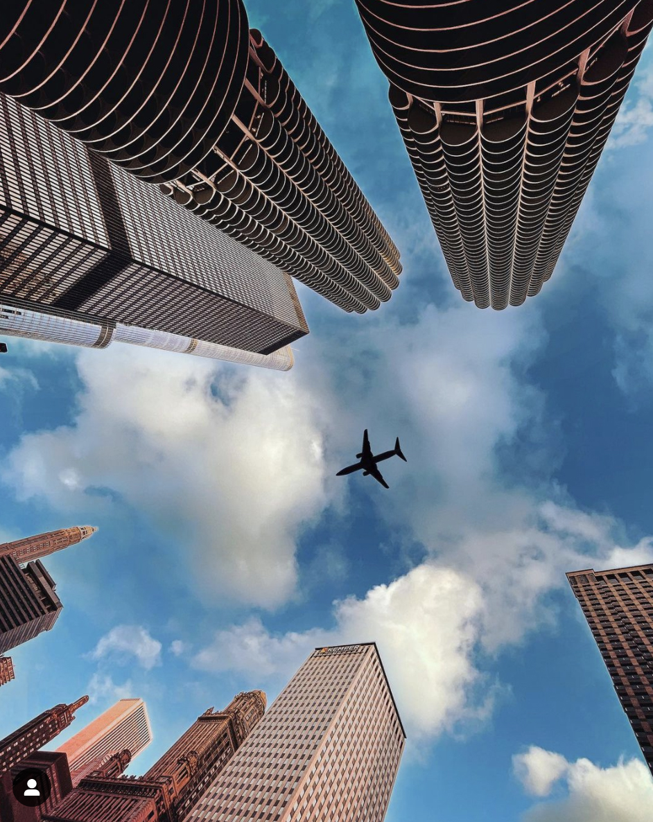 a plane flying in the sky above tall buildings