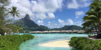 a beach with huts and a small island