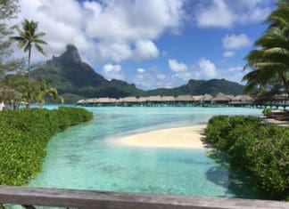 a beach with huts and a small island