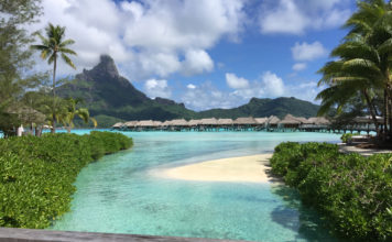 a beach with huts and a small island