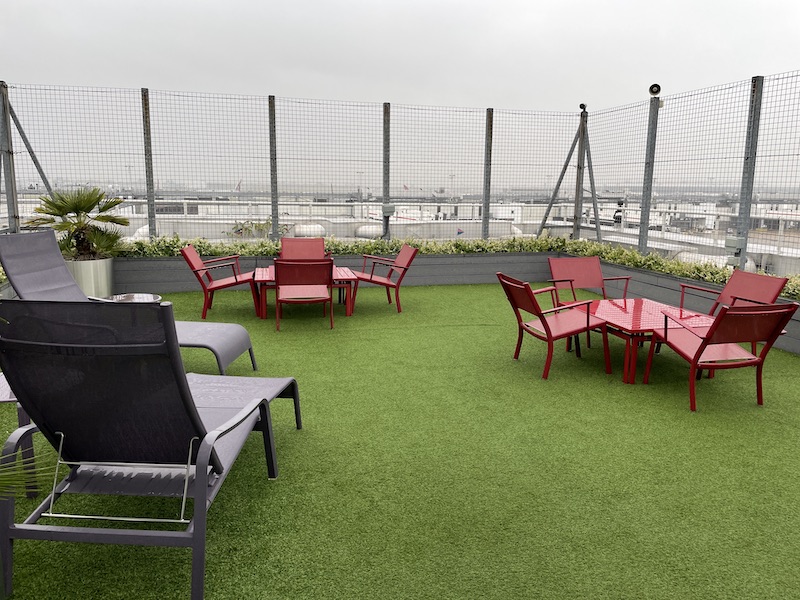 a patio area with chairs and tables on a green lawn