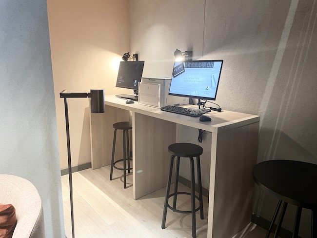 a desk with two computers and stools