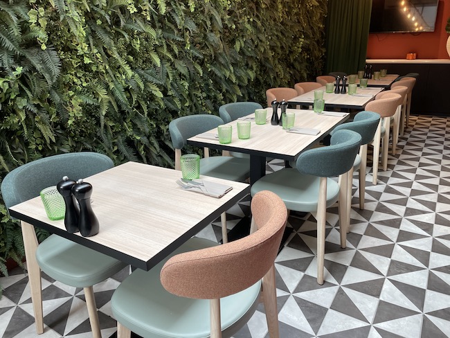 a table with chairs and a wall of plants