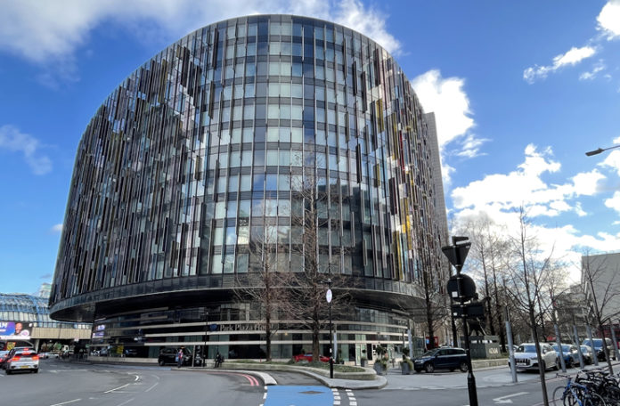 a circular building with many windows with Reichstag dome in the background