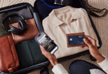 Review: The Hilton Honors American Express Aspire Card (175,000 bonus points & Diamond Elite status) a person holding a phone and a wallet next to luggage