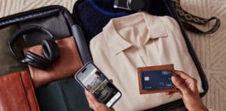 a person holding a phone and a wallet next to luggage