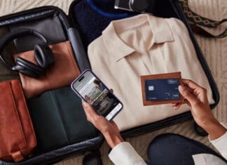 a person holding a phone and a wallet next to luggage