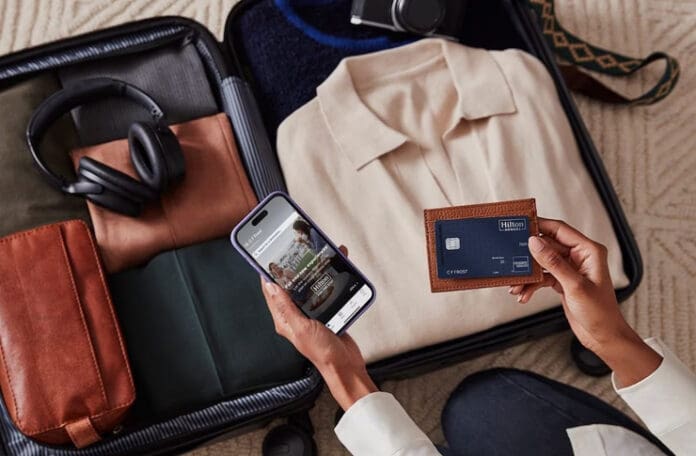 a person holding a phone and a wallet next to luggage