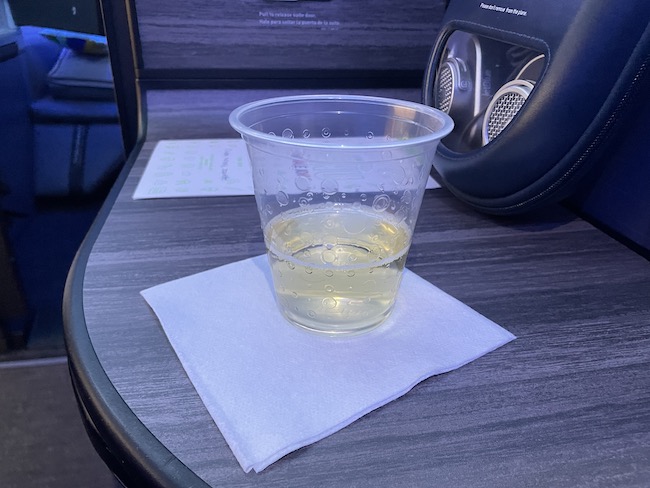 a clear plastic cup with yellow liquid on a napkin on a table