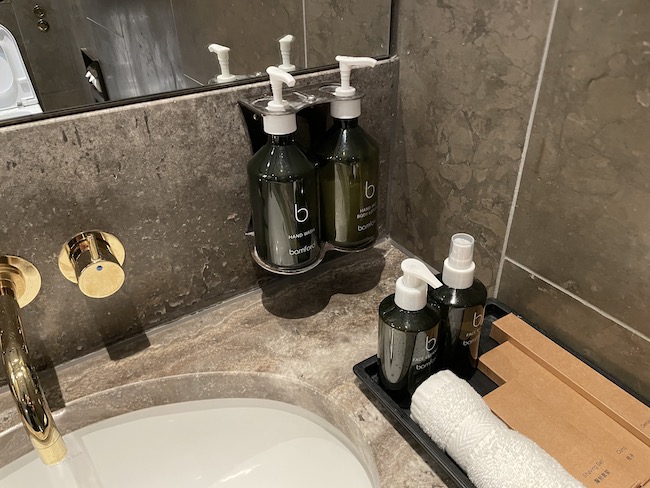 a bathroom sink with soap dispensers and a tray of toiletries
