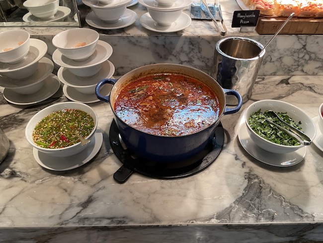 a large pot of soup and bowls of soup on a marble counter