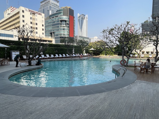 a pool with trees and chairs in front of buildings