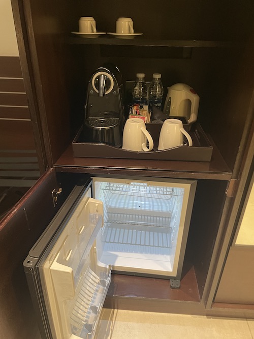 a small refrigerator with a coffee machine and cups inside