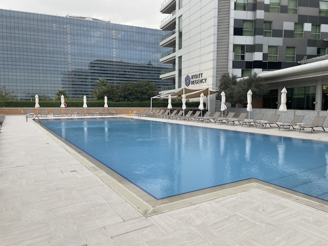 a pool with chairs and umbrellas in front of a building