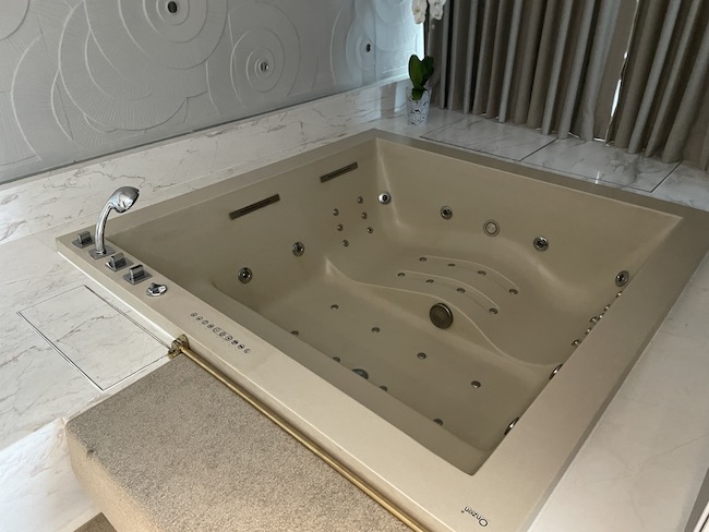 a large white bathtub with silver buttons