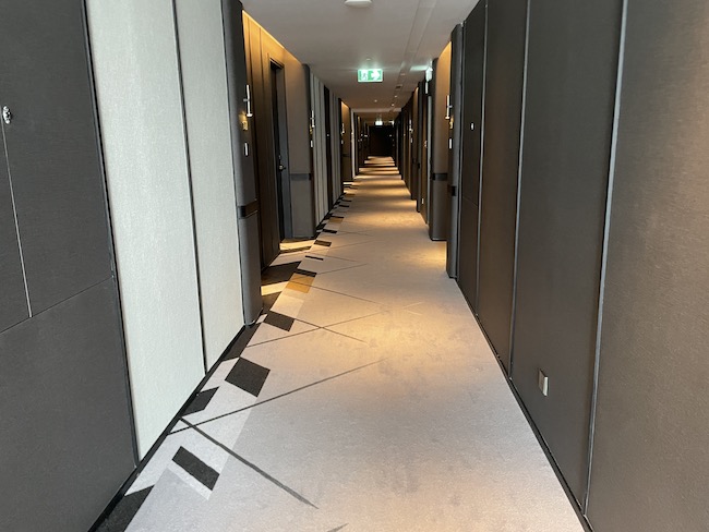 a long hallway with doors and a white and black floor