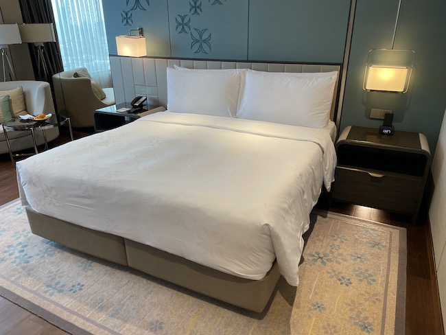 a bed with white sheets and a lamp on the side