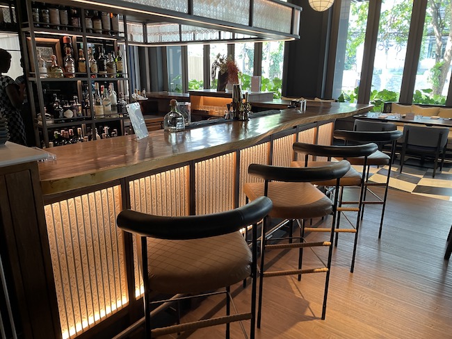 a bar with chairs and a shelf of liquor