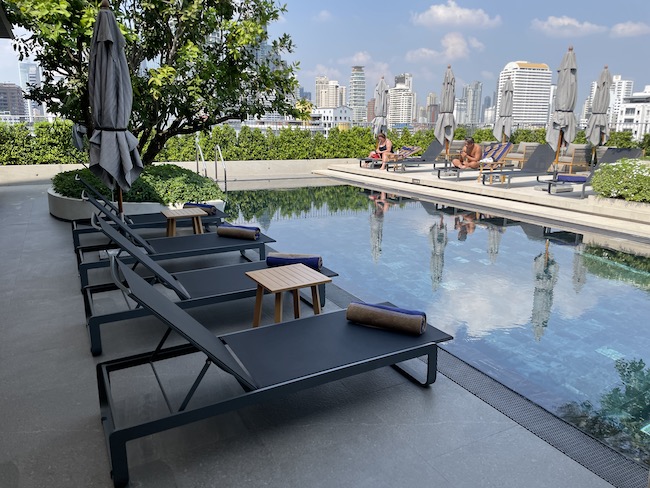 a pool with chairs and umbrellas by a building