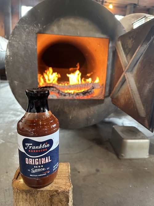a bottle of sauce in front of a fire in a wood oven