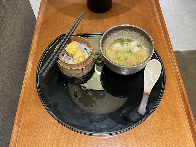 a bowl of soup and chopsticks on a black plate