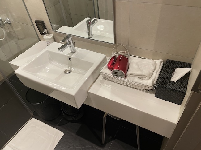 a bathroom sink with a mirror and a basket of red objects