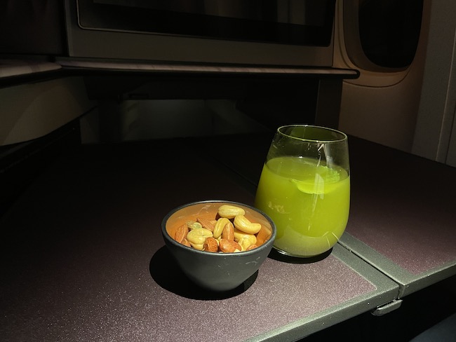 a bowl of nuts and a glass of juice on a table