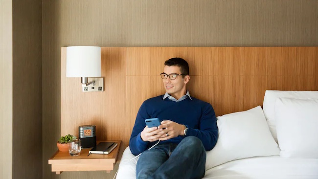a man sitting on a bed holding a phone