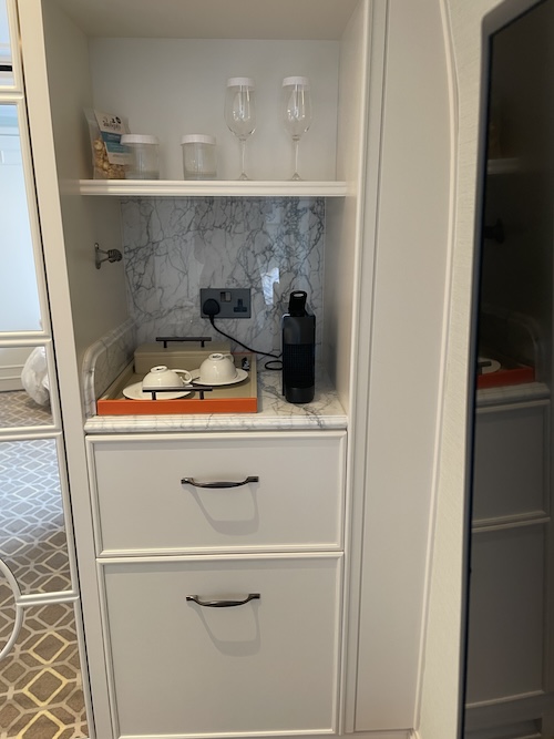 a white cabinet with a tea set and wine glasses
