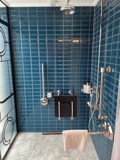 a blue tiled shower with a white towel on the wall