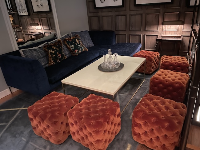 a living room with a couch and orange ottoman