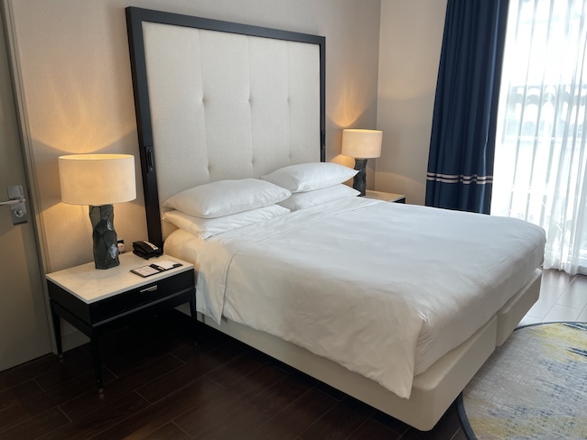 a bed with white sheets and a lamp next to a table