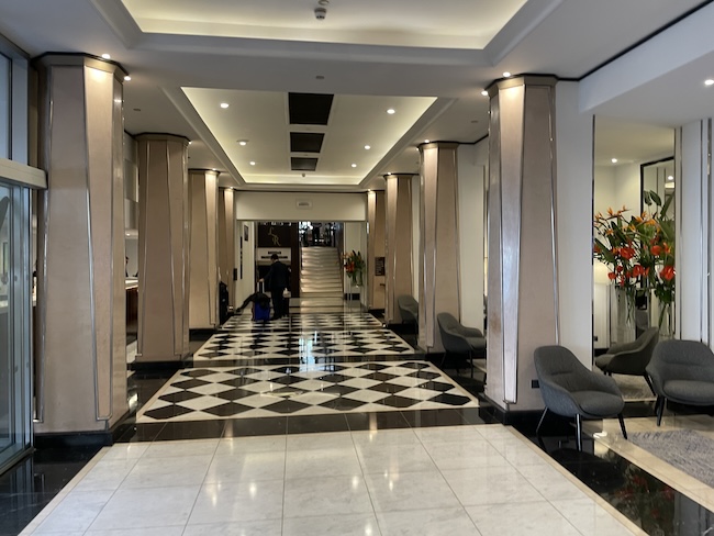 a black and white checkered floor with columns and chairs