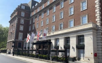 a building with flags and a fence