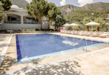 a pool with chairs and umbrellas in front of a building