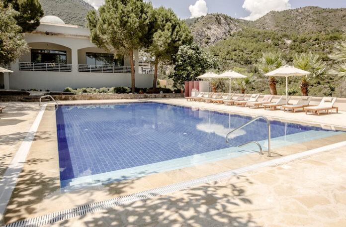 a pool with chairs and umbrellas in front of a building