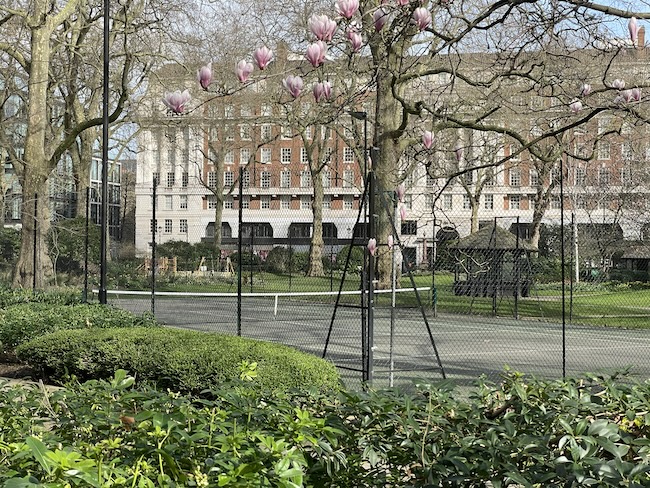 a tennis court with trees and a building in the background