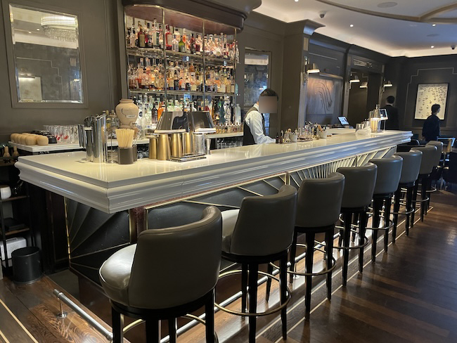 a bar with a row of chairs and a man behind it