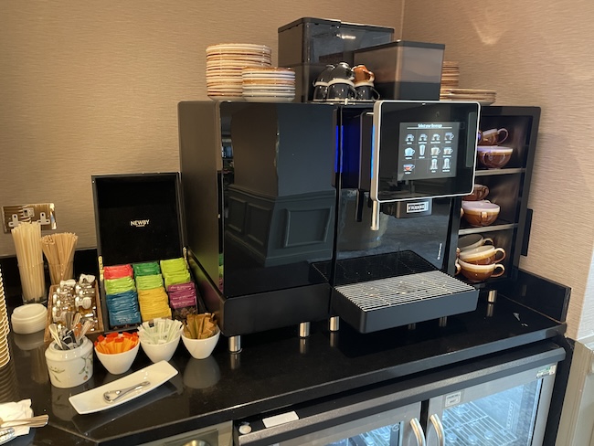 a coffee machine with a screen and cups on a counter