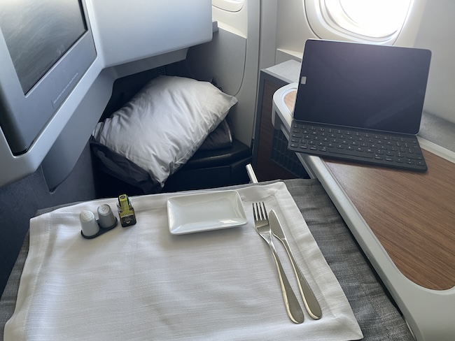 a table with a laptop and a plate and silverware on it